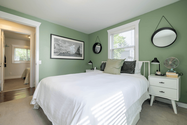 Bright bedroom featuring a cozy layout with fresh green walls and ample natural light.