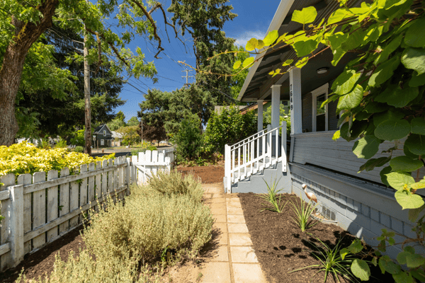 Welcoming entryway lined with lush greenery, leading to a bright and inviting front porch.