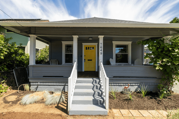 This inviting home features a vibrant yellow door, spacious front porch, and landscaped yard for outdoor enjoyment.