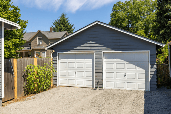 This spacious two-car garage features ample storage and easy access from a gravel driveway.