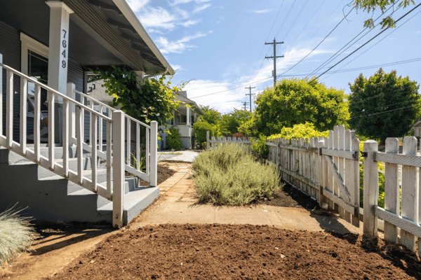Inviting entryway with landscaped garden beds and a spacious pathway, perfect for outdoor living.