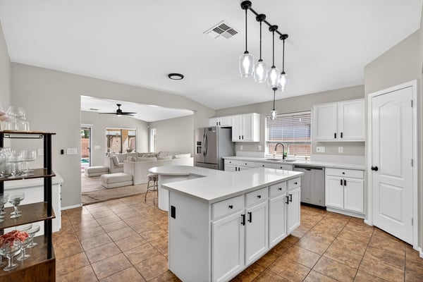 Spacious kitchen with large island, white cabinetry, and ample prep space. Open layout flows into living areas, making it ideal for gatherings in this Casa Grande property.