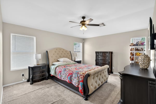 Generous primary bedroom with ceiling fan, soft carpet, and multiple windows. A relaxing retreat designed for comfort in this Casa Grande home.