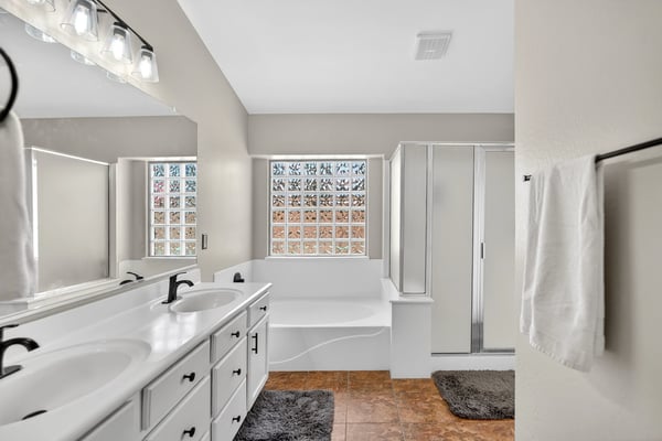 Bright primary bathroom with dual vanities, soaking tub, and walk-in shower. Functional layout offers everyday comfort in this Casa Grande property.