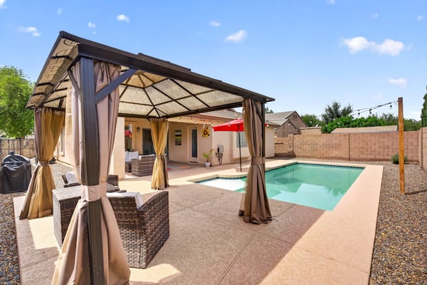 Backyard featuring a private pool and shaded pergola lounge area. Ideal for entertaining and enjoying warm Casa Grande evenings.