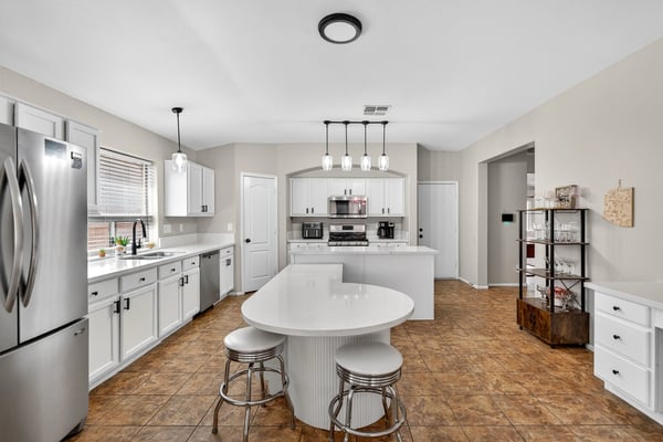 Functional kitchen with breakfast bar, white cabinets, and modern appliances. Seamless connection to living areas enhances flow in this Casa Grande home.