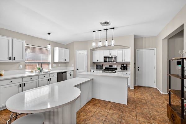 Bright open kitchen with large island, white cabinetry, and modern lighting. Perfect for entertaining and daily living in this Casa Grande home.