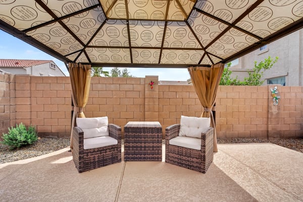 Backyard pergola with cozy seating creates a peaceful outdoor retreat. Perfect for relaxing near the pool in this Casa Grande home.