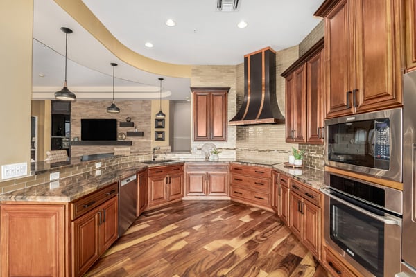 Stunning kitchen showcasing custom wood cabinetry, premium stainless appliances, decorative tile details, and a striking custom vent hood. A perfect blend of luxury, function, and everyday convenience.