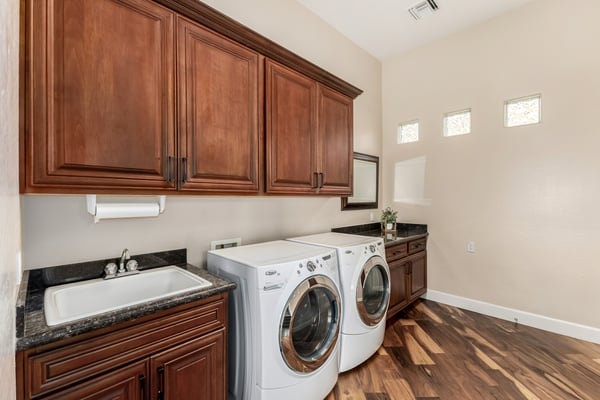 Spacious laundry room featuring extensive cabinetry, utility sink, storage solutions, and included appliances. Designed to make household tasks efficient and organized.
