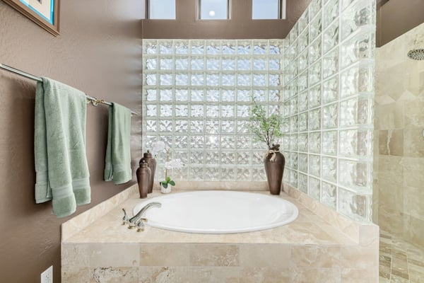 Beautiful soaking tub framed by glass block windows that fill the space with natural light while maintaining privacy. A standout feature of the spa-inspired primary bath.