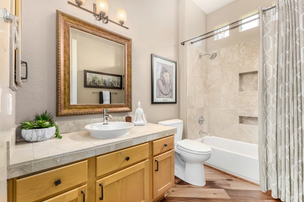 Tastefully finished guest bathroom with custom cabinetry, vessel sink, tile surround shower and tub, and abundant natural light. Thoughtful upgrades elevate everyday convenience in this Fountain Hills home.