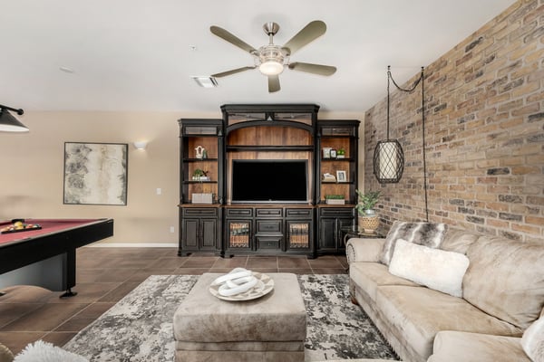 Inviting recreation space with custom built-in media cabinetry, stylish brick accent wall, and comfortable seating area. Perfect for movie nights, game-day gatherings, or creating a dedicated entertainment hub within the home.