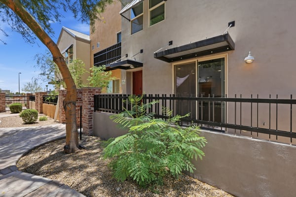 Attractive townhouse exterior featuring a private fenced patio, mature landscaping, and inviting architectural details. This Mesa home combines low-maintenance living with welcoming curb appeal.