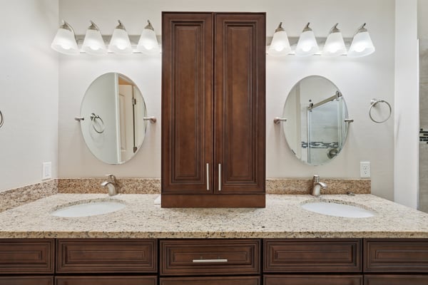 Primary bath featuring dual vanities, granite surfaces, abundant storage, and updated fixtures. The spacious layout provides convenience and a luxurious daily experience.