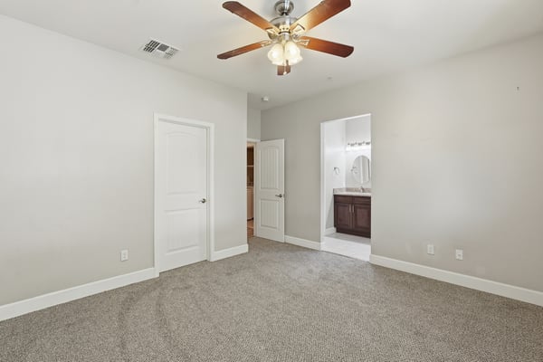 Large primary suite offering fresh carpeting, neutral colors, ceiling fan, and easy access to the ensuite bath and walk-in closet. A comfortable space to begin and end each day.