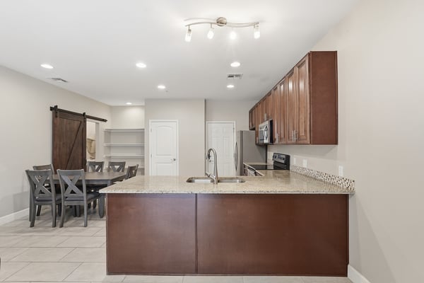 Large breakfast bar overlooking the living and dining areas creates the perfect gathering spot. Granite countertops and open-concept design add both beauty and functionality.