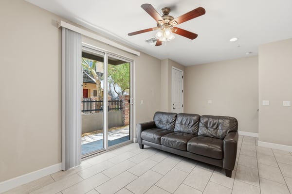 Comfortable living area with large sliding glass doors opening to the private patio. Natural light, tile flooring, and an open design enhance the home's inviting atmosphere.