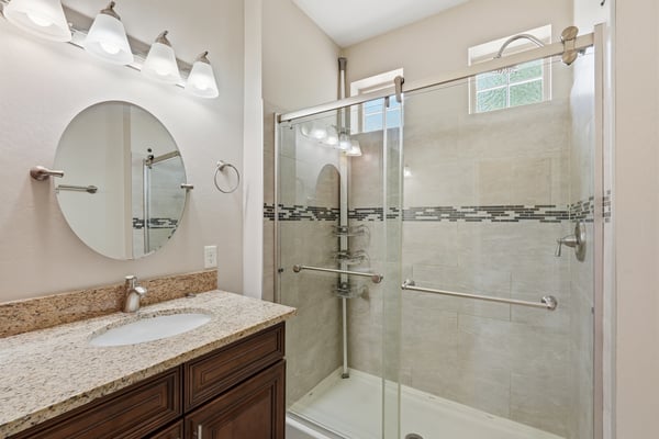 Elegant walk-in shower with glass enclosure, tile surround, and contemporary finishes. Paired with a granite vanity, this bathroom offers both style and convenience.
