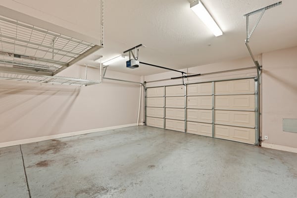 Large two-car garage featuring overhead storage systems, ample parking space, and room for tools or recreational equipment. Designed for both convenience and organization.