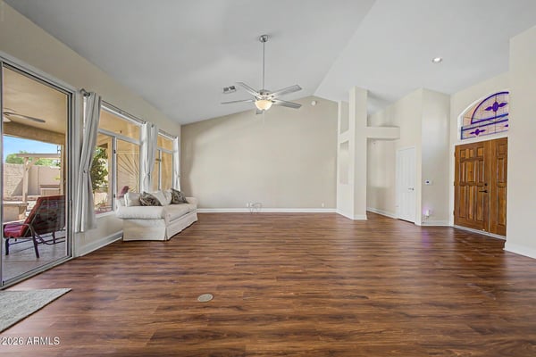 Large windows and patio doors bring in natural light while showcasing the backyard setting. The spacious layout and vaulted ceilings create a bright and welcoming atmosphere throughout the main living area.