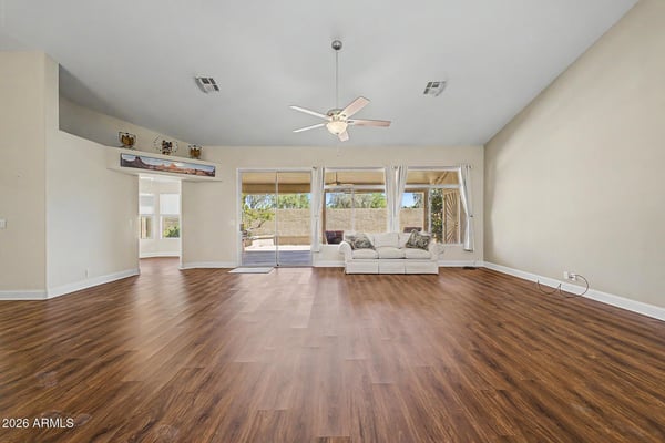 Sliding glass doors connect the living space to the covered patio, creating an ideal setup for entertaining. Updated flooring and soaring ceilings enhance the room's open and inviting feel.