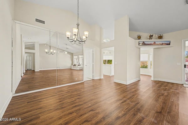 A stylish chandelier, mirrored wall accents, and rich flooring define this inviting dining area. Conveniently positioned within the open floorplan, it offers the perfect setting for gatherings and celebrations.