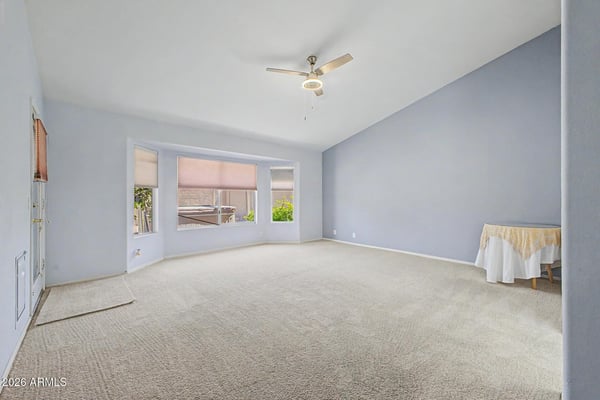 Large windows, vaulted ceilings, and neutral finishes make this spacious primary suite feel bright and welcoming. The flexible layout easily accommodates a variety of furniture arrangements and personal styles.