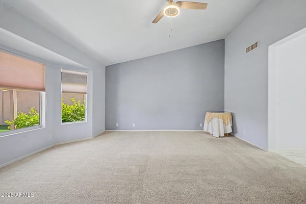 This generously sized primary suite offers plush carpeting, soothing paint colors, and abundant natural light. The comfortable design creates a peaceful space for relaxation and rest.