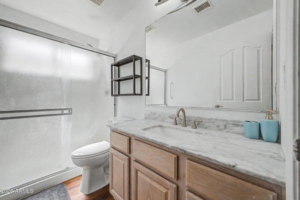 Updated finishes highlight this bathroom, including a stylish vanity, modern fixtures, and a convenient shower enclosure. The clean design enhances functionality while maintaining a fresh, contemporary feel.