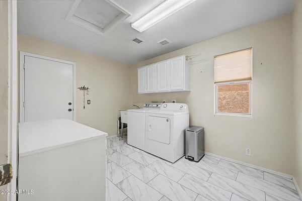Designed for convenience, this large laundry area includes upper cabinetry, extensive floor space, and durable tile flooring. The practical layout supports storage, organization, and household efficiency.