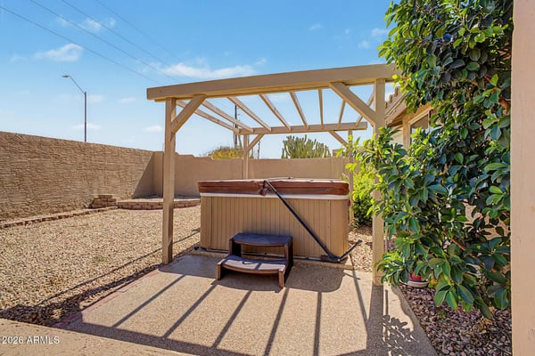 Relax in the private backyard spa nestled beneath a pergola-style shade structure. Easy-care desert landscaping and a peaceful outdoor setting make this space perfect for year-round enjoyment in Peoria.