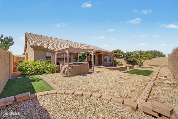 Featuring a pergola-covered spa, attractive desert landscaping, and spacious outdoor living areas, this backyard creates a private retreat perfect for relaxing and entertaining guests in Peoria.