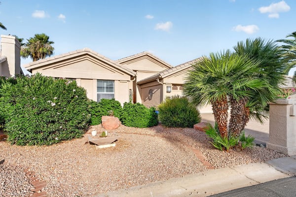 Low-maintenance desert landscaping, mature greenery, and decorative accents create an inviting front yard. This attractive outdoor setting enhances the home's curb appeal and complements the Arizona lifestyle.