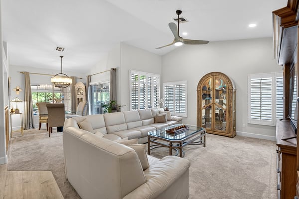 The open layout combines living, dining, and kitchen spaces into one cohesive design. Plantation shutters, vaulted ceilings, and abundant natural light create an airy and inviting environment.