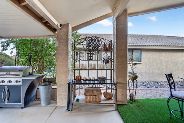 A beautifully maintained backyard with mature trees, decorative pathways, desert landscaping, and attractive garden accents. The low-maintenance design complements the home's outdoor living spaces.