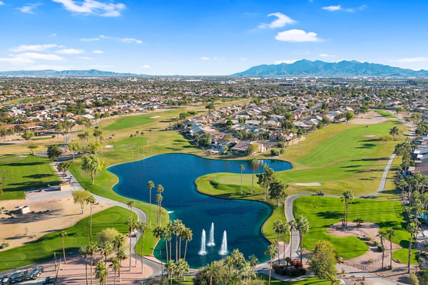 Panoramic aerial views capture lakes, fairways, palm trees, and expansive green spaces that define this impressive golf course community in Goodyear.