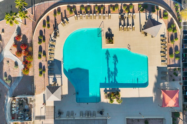 A bird's-eye view of the community pool reveals spacious deck areas, shaded seating, and attractive landscaping. Residents enjoy resort-inspired amenities designed for relaxation and recreation.