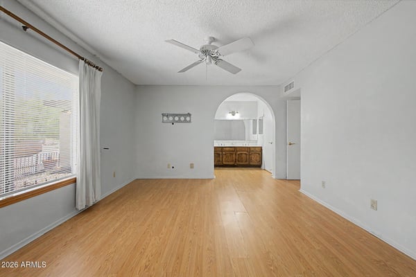 Bright and welcoming, this primary bedroom features a generous footprint and neutral finishes. Large windows and durable flooring contribute to the room's comfortable and inviting feel.