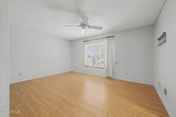 This spacious primary suite features neutral finishes, durable flooring, and abundant natural light. The flexible floorplan allows for comfortable furnishings while creating a peaceful retreat within the home.