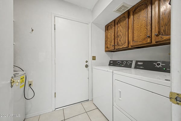 Complete with upper storage cabinets and included laundry appliances, this dedicated laundry room offers efficiency and convenience. The practical layout helps maximize organization and household functionality.