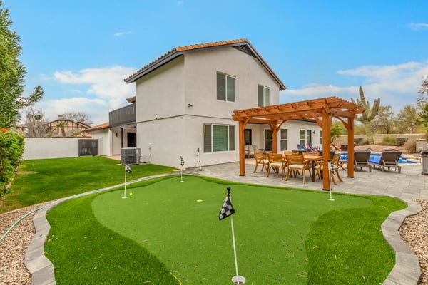 Incredible backyard with a private putting green, pergola-covered dining area, spacious patio, poolside gathering spaces, and lush landscaping. This Scottsdale property offers exceptional outdoor enjoyment.
