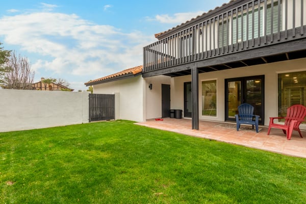 Spacious backyard highlighted by a covered patio, second-story balcony, and lush green lawn. A versatile Scottsdale outdoor space perfect for recreation, pets, and entertaining.