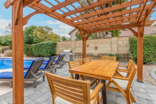 Custom pergola-covered dining area positioned beside the pool and lounge deck. This Scottsdale backyard creates the perfect atmosphere for outdoor meals and entertaining.