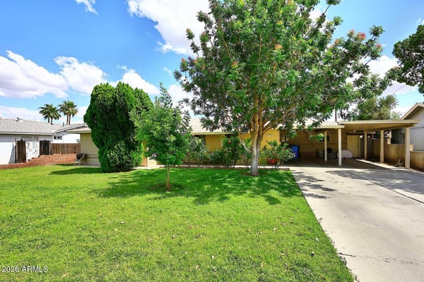 Mature trees, lush lawn, and a spacious driveway contribute to the home's welcoming curb appeal. The well-maintained front yard enhances the overall presentation of this Phoenix property.