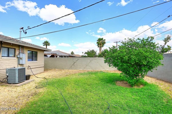 A spacious fenced backyard with mature landscaping and a large lawn creates a welcoming environment for outdoor enjoyment. The generous lot provides flexibility for recreation, pets, gardening, or future improvements.