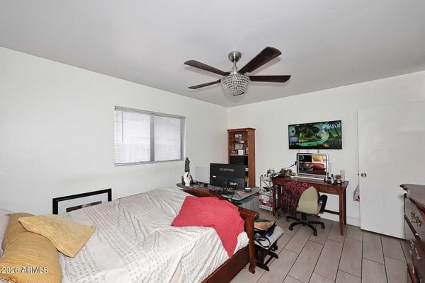 The primary bedroom offers generous square footage, abundant natural light, and versatile space for relaxation and productivity. Tile flooring and a ceiling fan add everyday comfort.