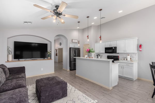 The stylish kitchen showcases white quartz countertops, white cabinetry, recessed lighting, a spacious breakfast bar, and open sightlines to the family room, making meal preparation and entertaining easy.