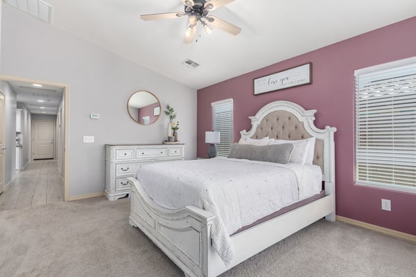 Unwind in the spacious primary suite offering plush carpet, large windows, neutral colors, and generous room for a sitting area or additional furnishings, creating a relaxing retreat.