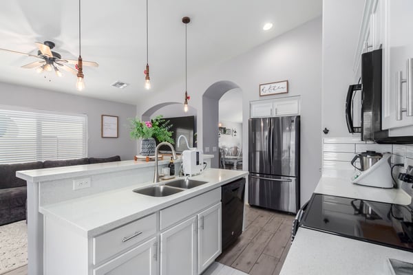 White quartz countertops, crisp white cabinetry, a spacious breakfast bar, and an open floor plan make this stylish kitchen the heart of the home. Perfect for entertaining and everyday living.